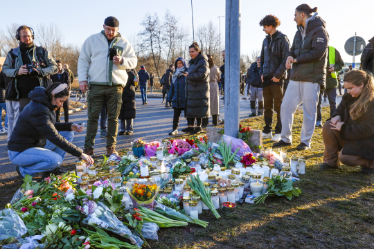 Personer legger ned blomster og lys på bakken for å minnes ofre