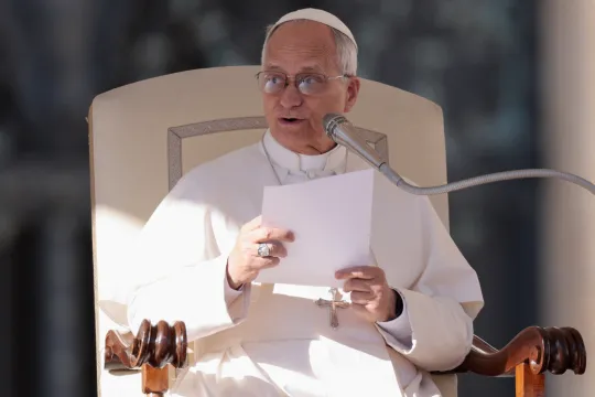 Pave Leo XIV sitter på en stol på Petersplassen og leser fra et ark