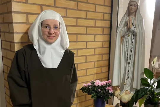 Karmelittsøster står ved siden av en statue av Jomfru Maria