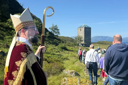 Biskop Fredrik hansen ser ut over havet. I bakgrunnen: Klostertårnet til Selja kloster