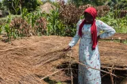 Kvinne i Uganda står ved siden av et såbed og smiler