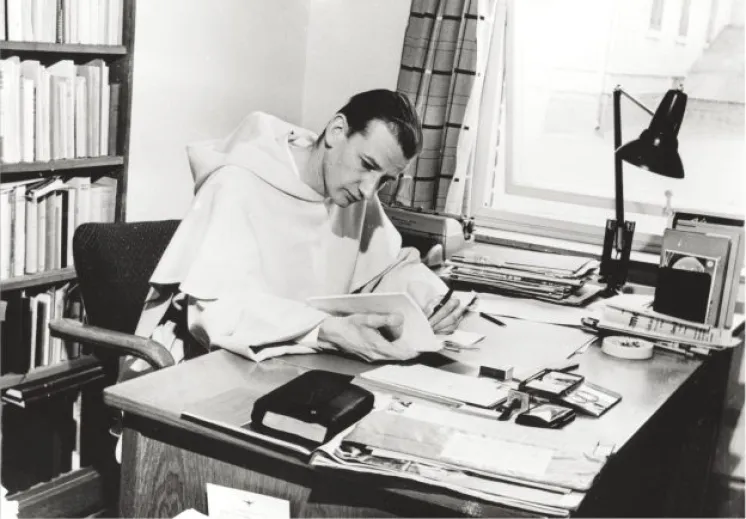 Erik Gunnes ikledd hvit dominikanerdrakt sitter ved et skrivebord med bøker