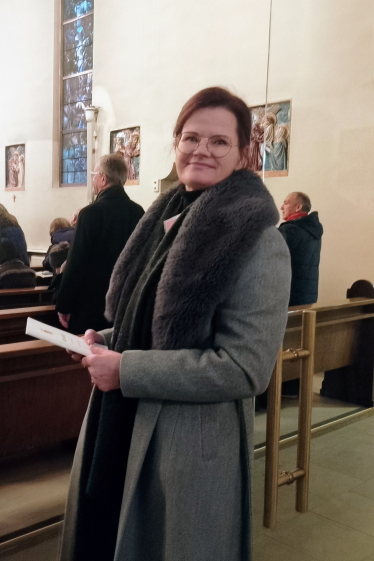 En kvinne ikledd ytterkåpe står ved døren til kirkerommet i St. Joseph kirke og ser mot kamera