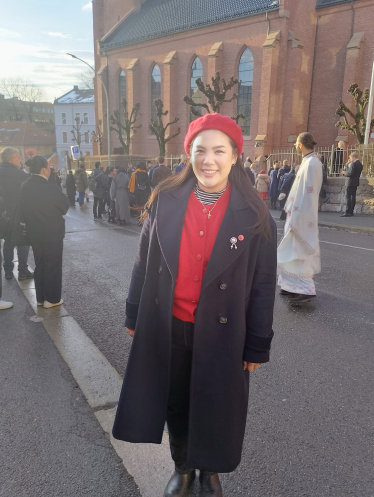 En ung kvinne står i Akersveien foran en folkemengde utenfor St. Olav domkirke