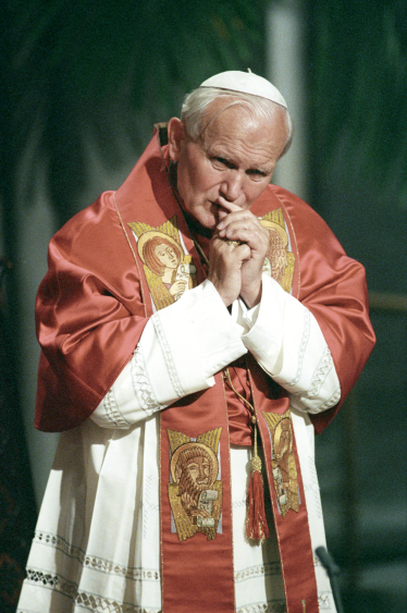 Pave Johannes Paul II ber stående i røde og hvite messeklær