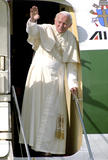 Pave Johannes Paul II, ikledd hvitt, hilser fra døren til et fly