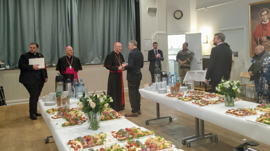 Kardinal Parolin og erkebiskop Julio Murat hilser på troende i menighetssalen ved St. Olav domkirke i Oslo