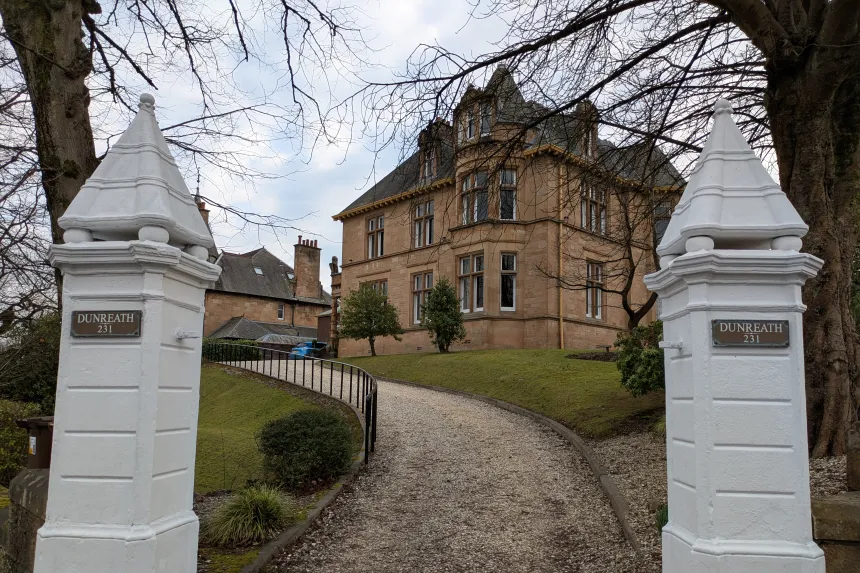 En sti leder opp mot et stort steinhus på toppen av en liten høyde