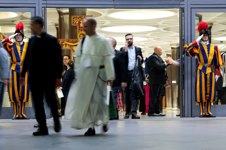 Geistlige og legfolk på vei ut av Paul VI-hallen i Vatikanet, med en sveitsergardist på hver side