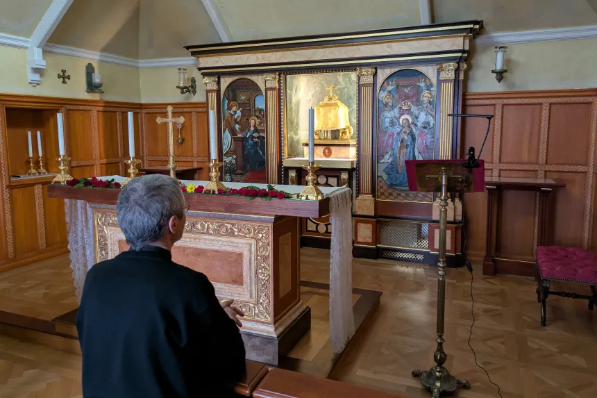 En prest ber i et lite kapell med alter, tabernakel og religiøs kunst