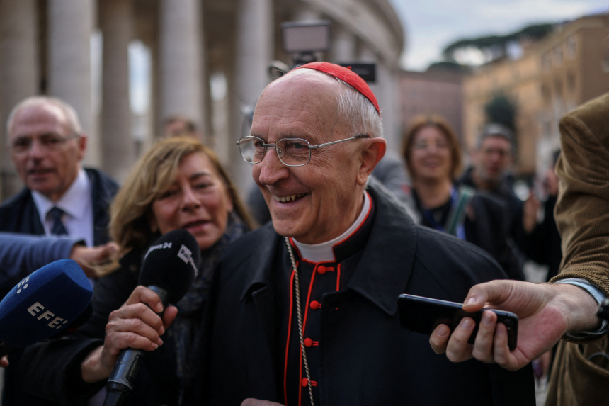 Kardinal Filoni smiler, omgitt av reportere med mikrofoner på gaten i Roma