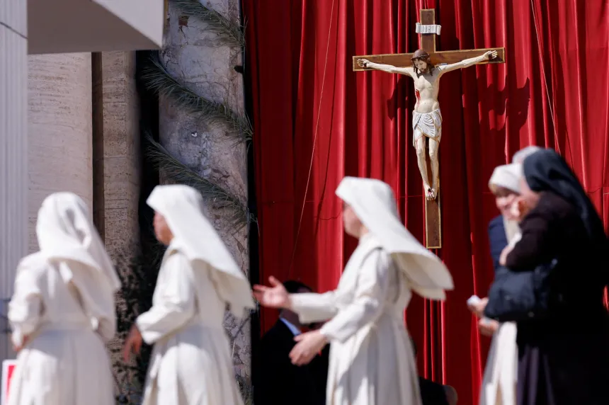 Ordenssøstre går forbi et krusifiks på Petersplassen
