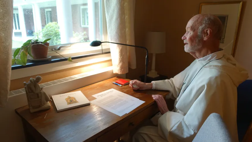 Arne Fjeld sitter ved skrivebord i dominikanerdrakt