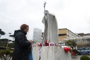 En person går forbi statuen av avdøde pave Johannes Paul II utenfor Gemelli-sykehuset i Roma, der pave Frans får behandling. 