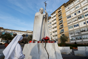 En nonne står ved siden av statuen av pave Johannes Paul II utenfor Gemelli-sykehuset i Roma