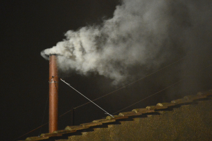 Hvit røyk kommer ut av en tynn metallpipe i Vatikanet