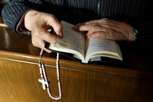 Hender holder en rosenkrans og en bibel med kinesisk skrift