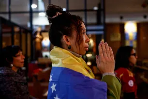 Kvinne kledd i et venezuelansk flagg ber i en kirke